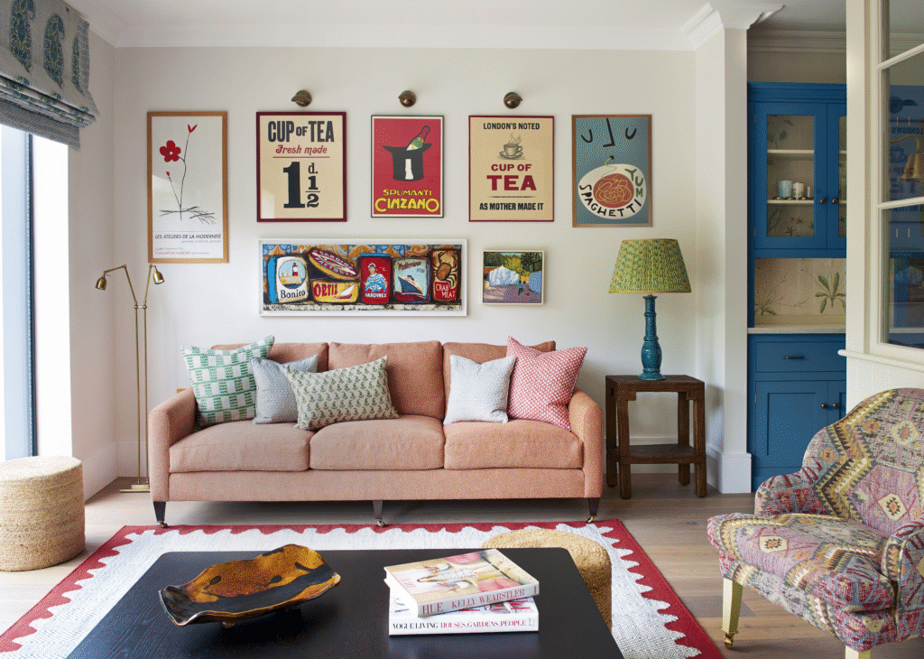 Bright living room with a coral sofa, patterned pillows, and a colorful gallery wall of vintage inspired posters and artwork above, next to a teal cabinet and patterned armchair.