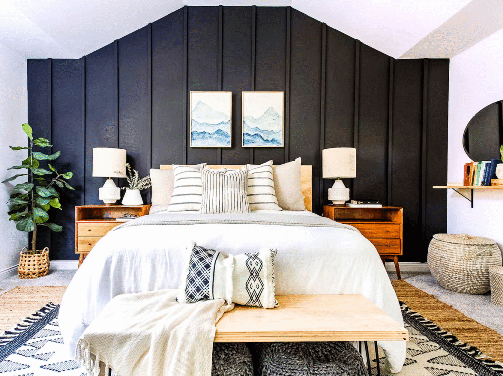 Modern bedroom with a dark feature wall, light wood bed and nightstands, white and striped bedding, and soft layered textiles that frame the furniture.