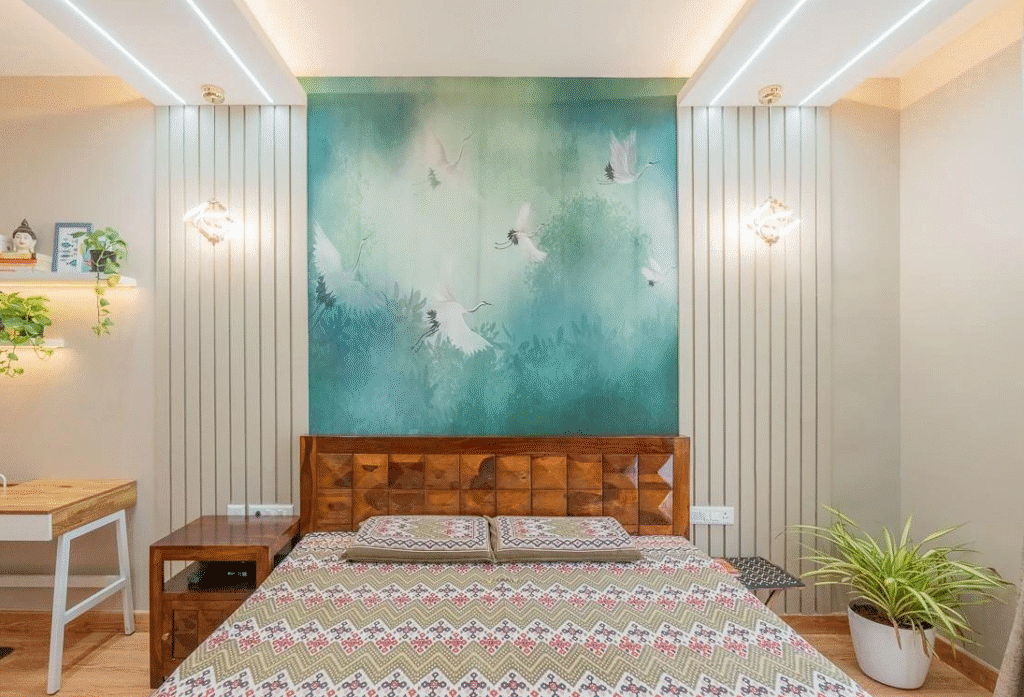 Bright modern bedroom with a wooden bed and patterned bedding, set against a large teal green mural of flying white birds and foliage, with slim vertical wall panels, pendant lights, and potted plants on each side.