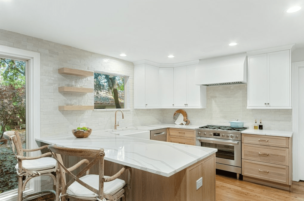 Bright white and light wood kitchen with a quartz peninsula, floating shelves, and simple decor showing how layered small updates can refresh the space.