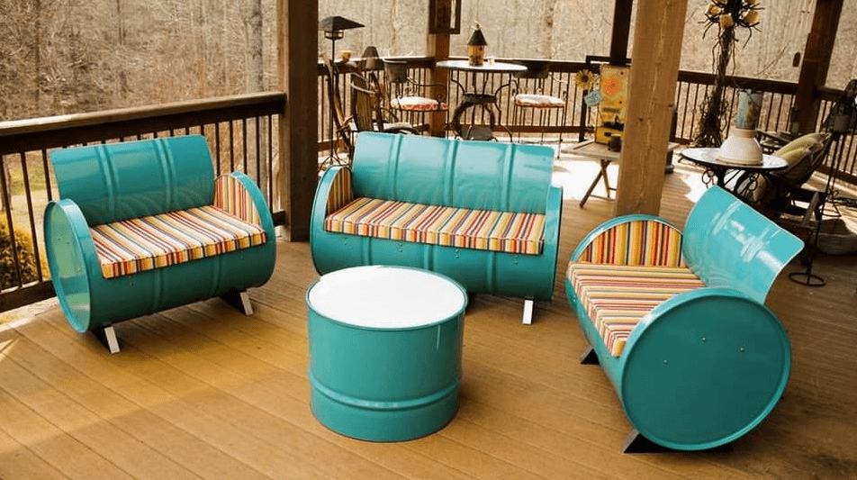 Teal barrel furniture set on a covered patio, with striped cushions and a round barrel coffee table on a wooden deck.