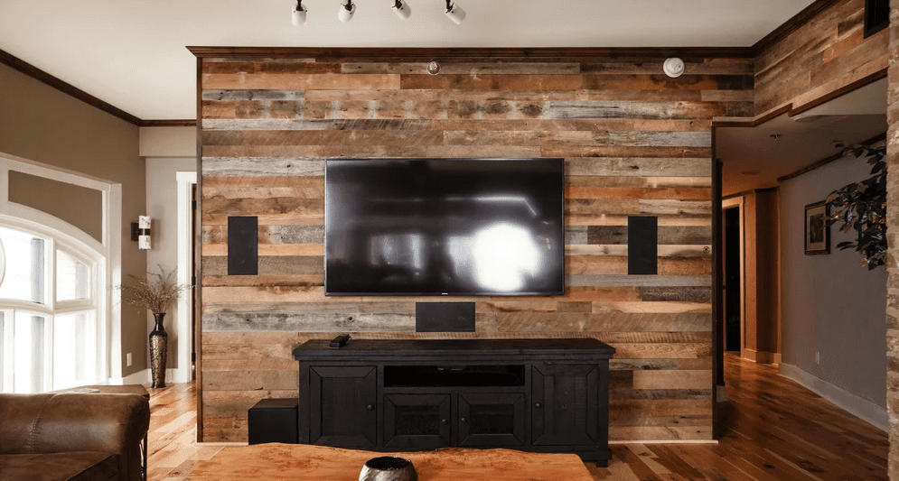 Cozy living room with a large television mounted on a reclaimed barn wood accent wall above a black media console.