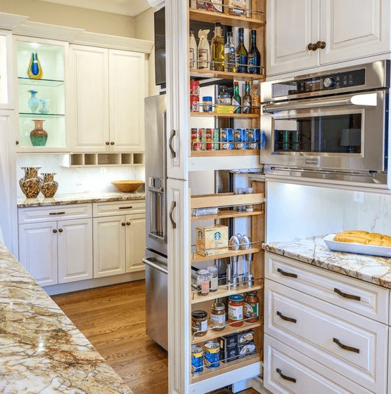 Bright kitchen with cream cabinets and tall pull out pantry shelves neatly stocked with cans, jars, and bottles for rustic style storage